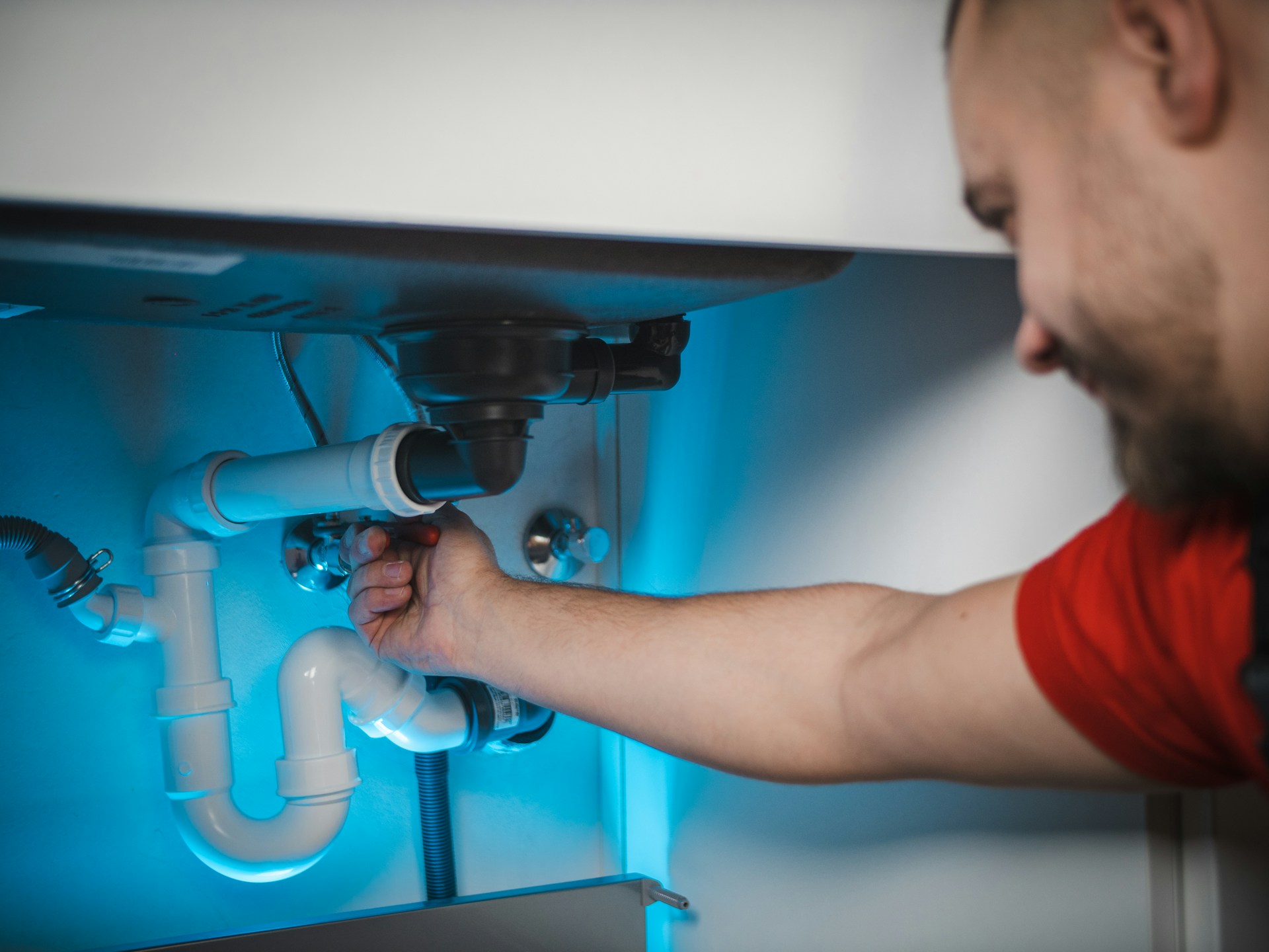 Plumber fixing under-sink pipes